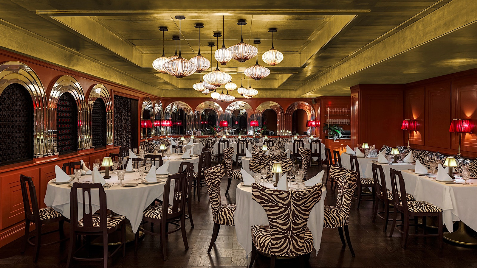  El comedor opulento con detalles dorados y rojos y sillas con estampado de cebra en Dirty French Steakhouse en Miami